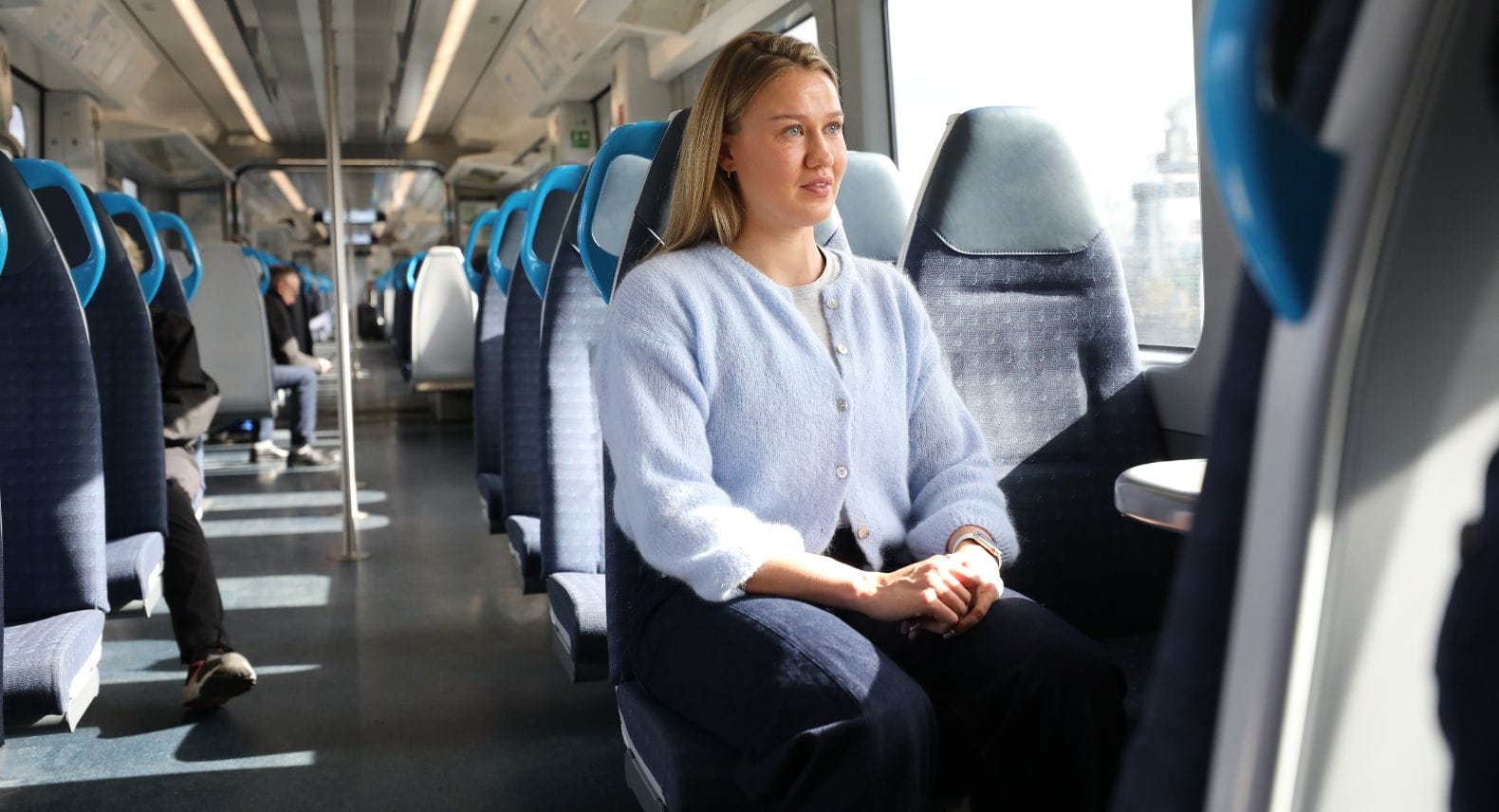 Blonde woman sitting on a train looking out of the window