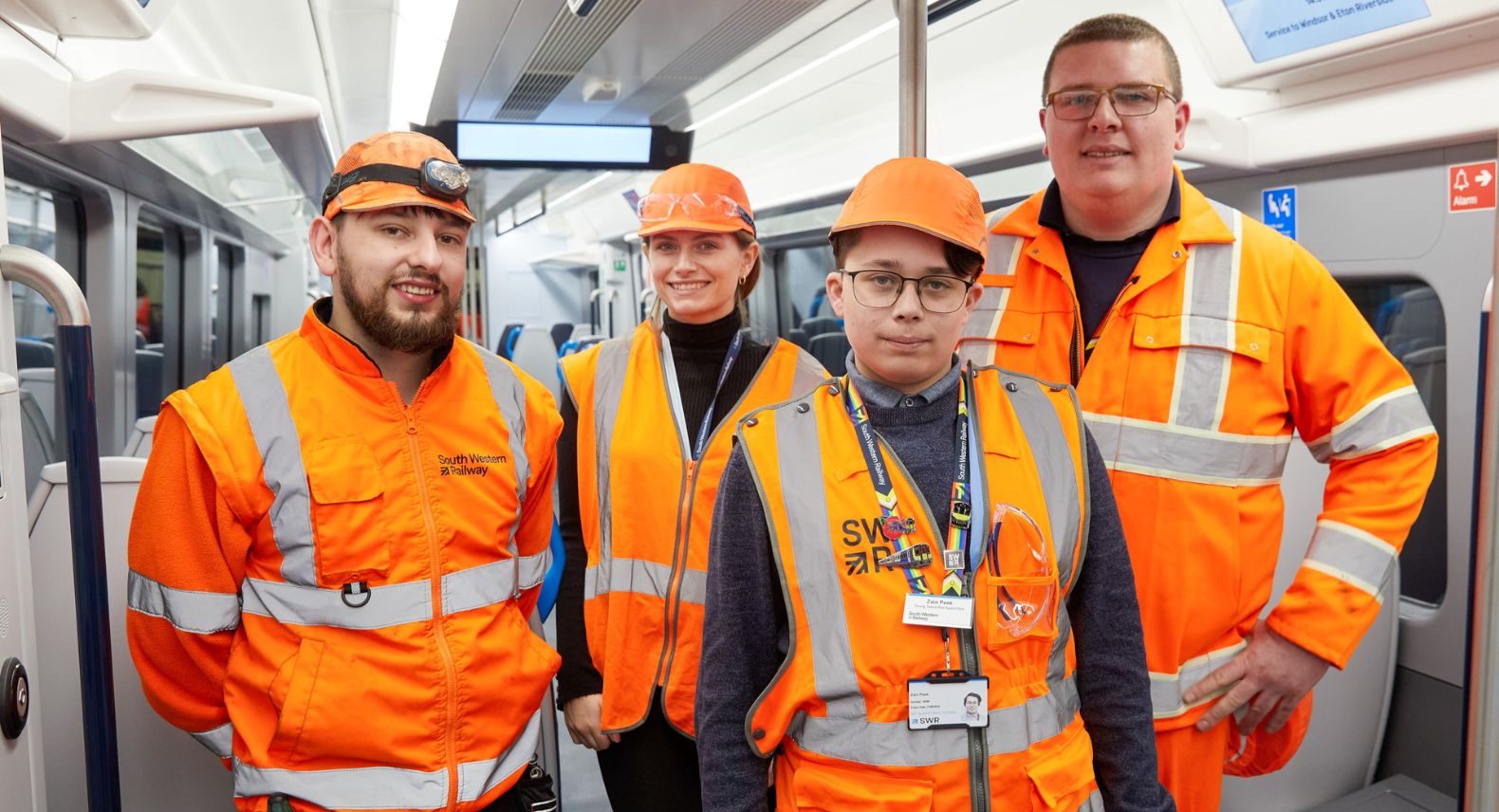 Group of four people in Hi-vis clothing standing in the lobby of an Arterio train