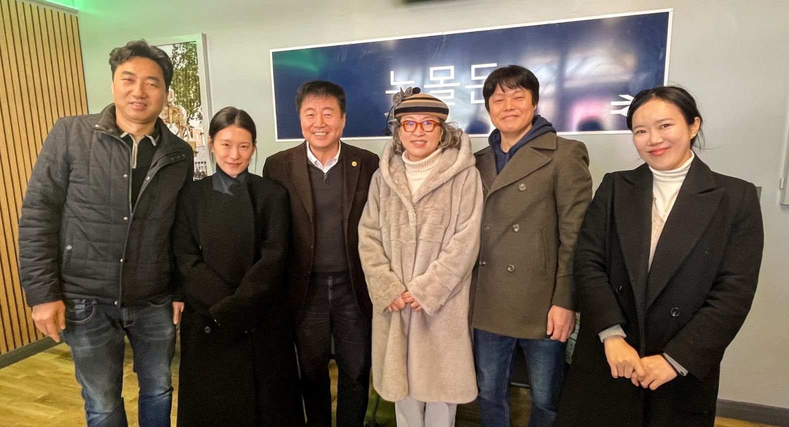 Group of Korean people in front of a sign saying New Malden in Korean in station waiting room