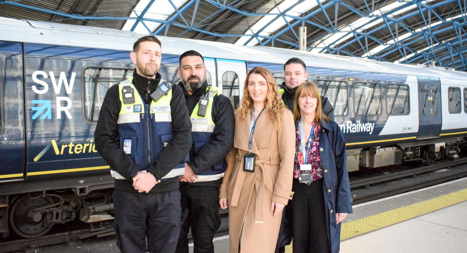 Group of five safeguarding colleagues standing in front of a train at platform at London Waterloo