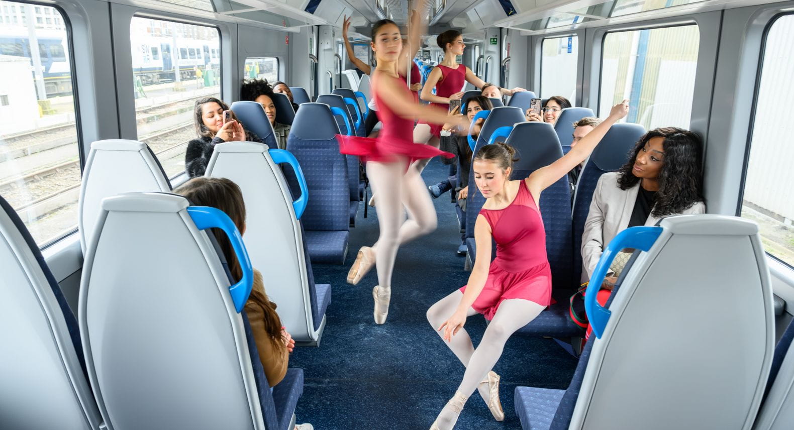 Group of young ballet dances performing in front of customers on an Arterio train