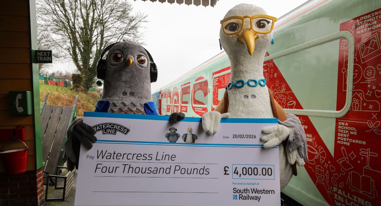 Oversized pigeon and seagull mascots holding a giant cheque between them