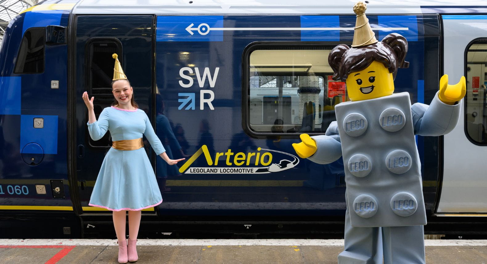 Girl and adult-size LEGO mini figure standing in front of an SWR Arterio train called the LEGOLAND Locomotive