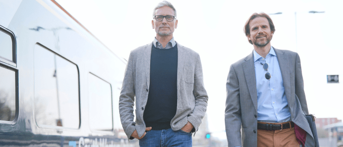2 professional guys walk along the train platform