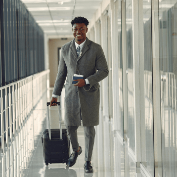 Business traveller walking through a modern airport corridor with suitcase and passport.