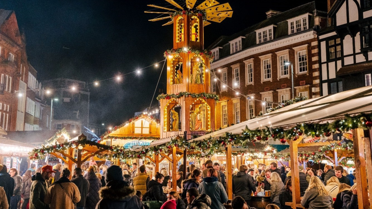 A group of people at Christmas market stalls.