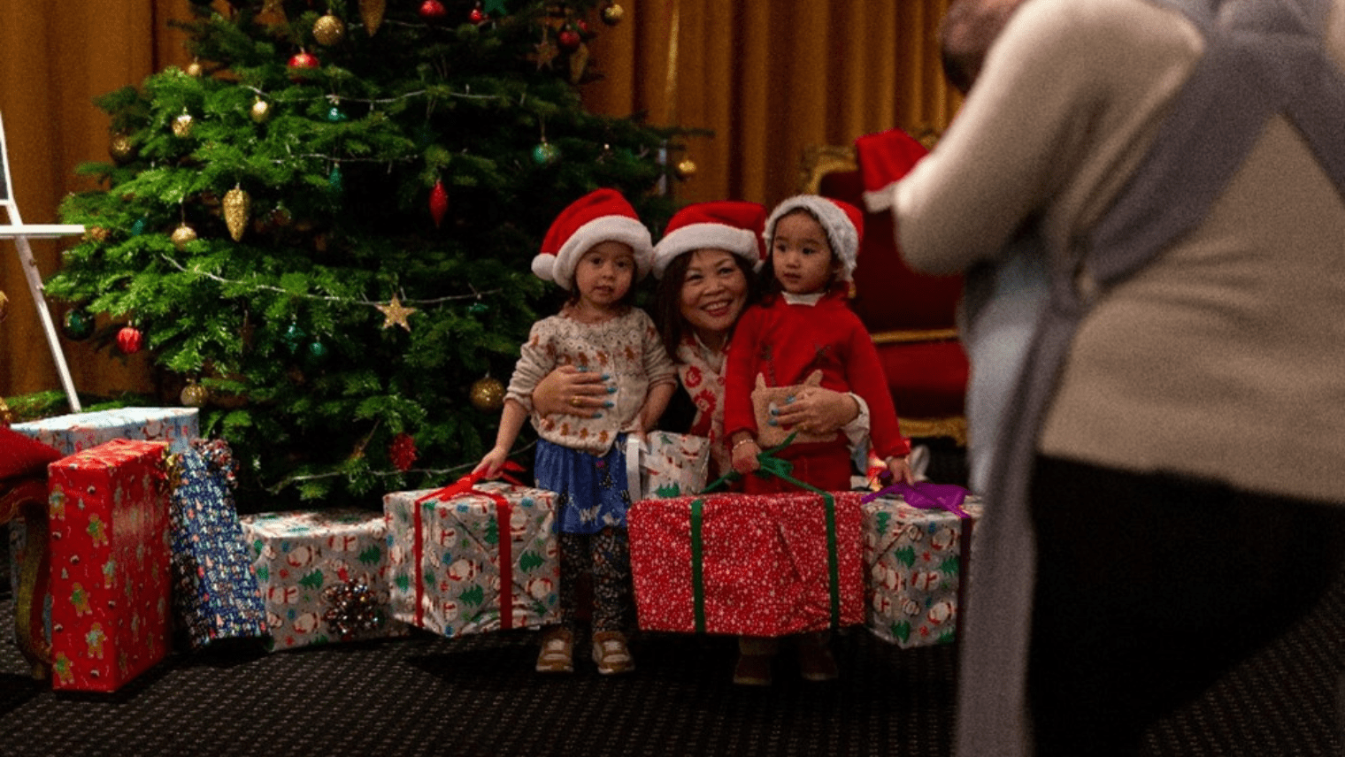 Families posing for photos by a Christmas tree