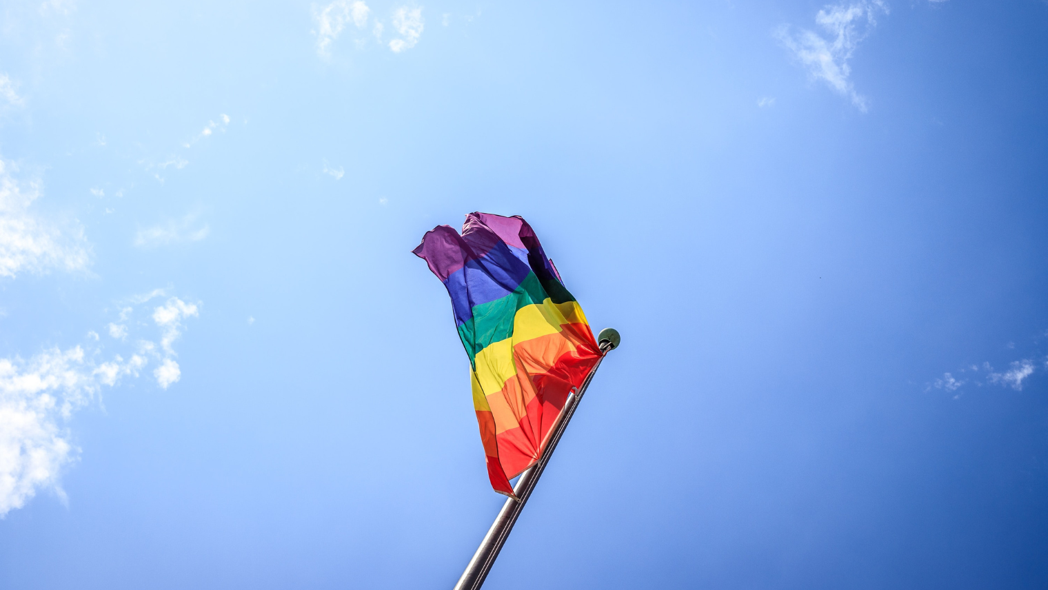 Image of a flag on a tall pole, with the sky in the background