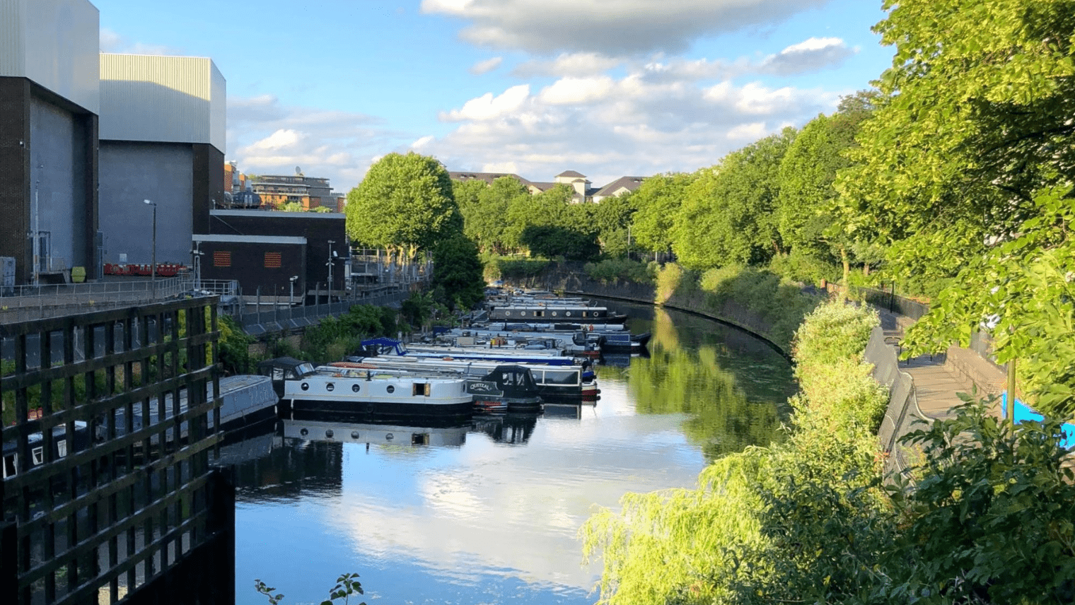 Multiple boats parked up on a river, surrounded by buildings