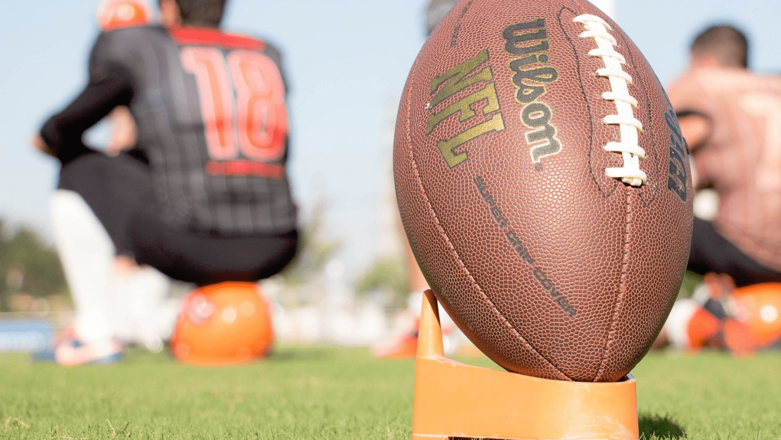 American football on a pitch with player sat in front of it