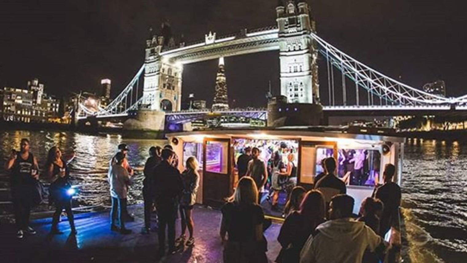 Friends on a Thames cruise with a view of Tower Bridge at night