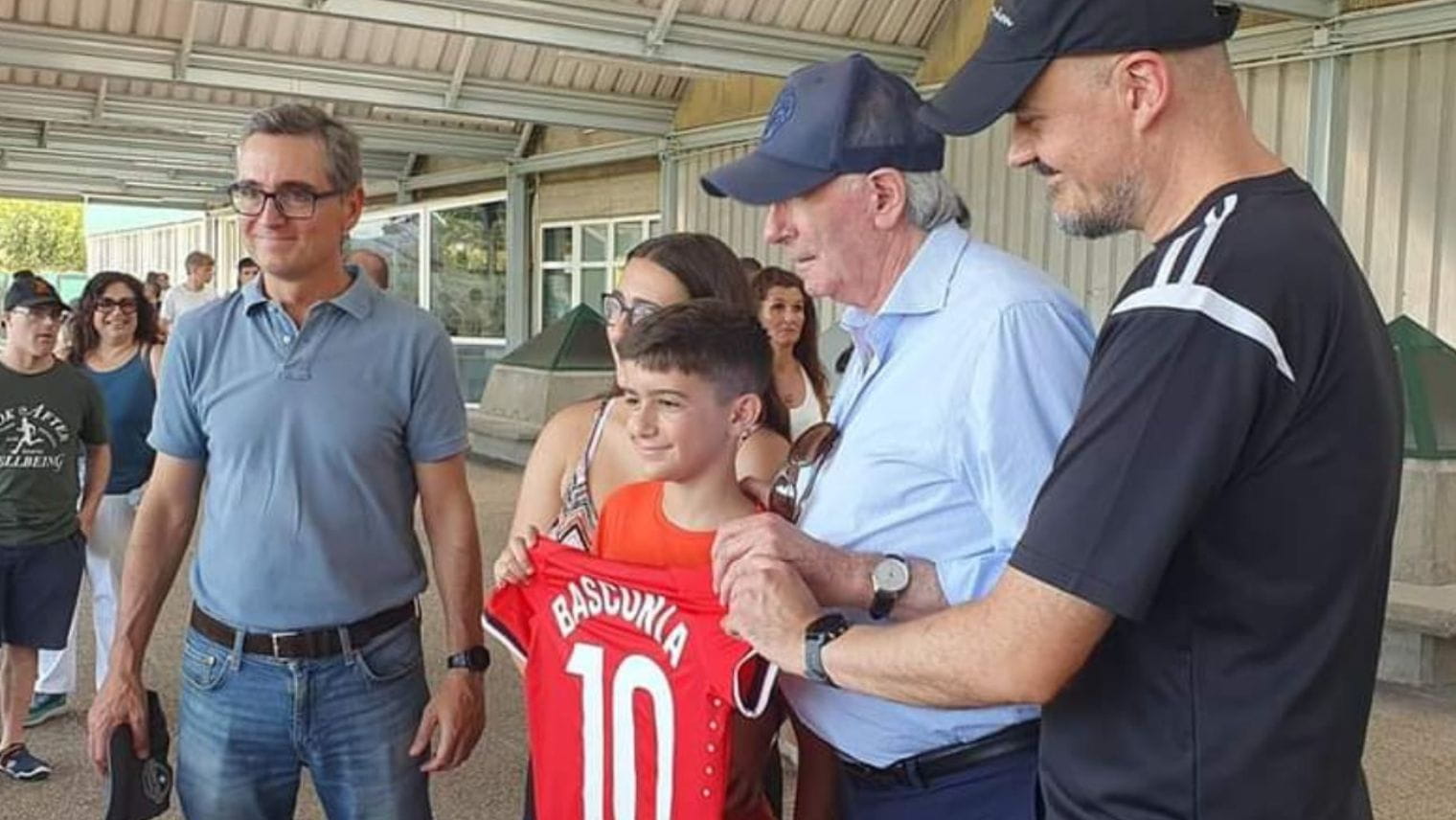 A kid holding a football t-shirt, taking a picture with Non-League Day teams