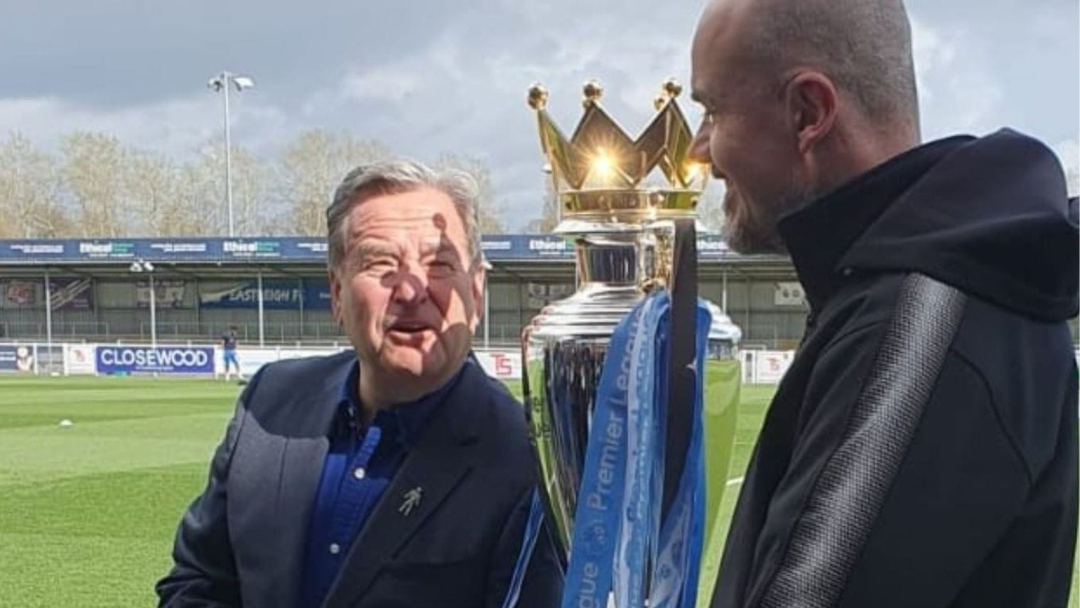 2 people holding the Non League Day football trophy