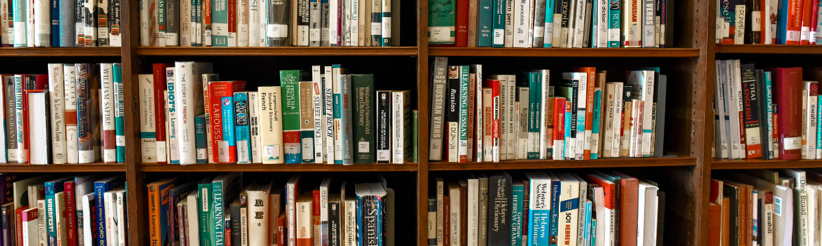 A library bookshelf filled with a variety of books, many focused on language learning and reference. The spines show titles such as French dictionaries, grammar guides, and other educational texts, all neatly arranged with library labels.