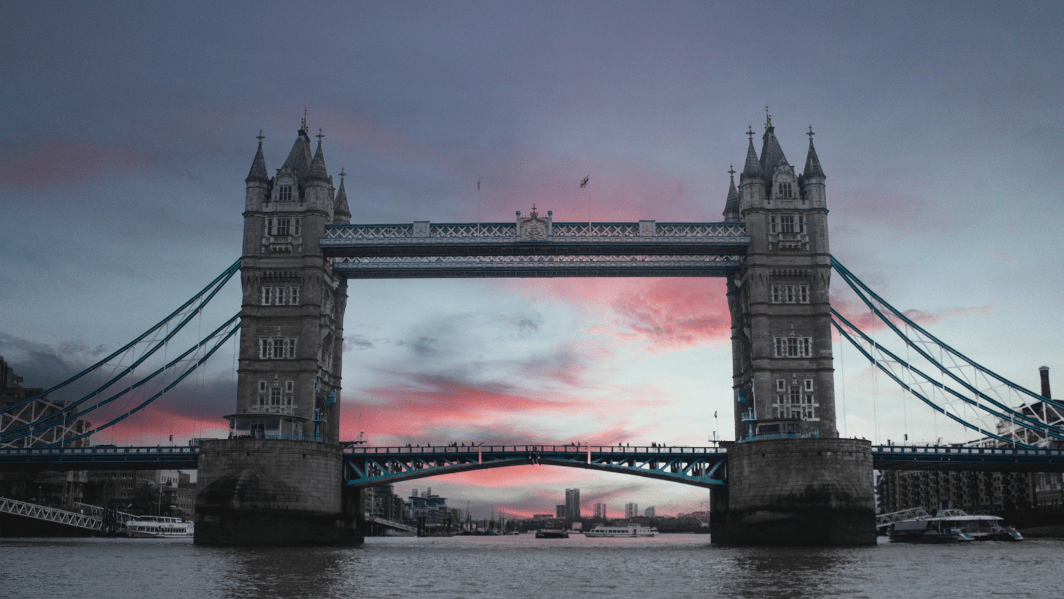 Tower Bridge at sunset with boats on the Thames.