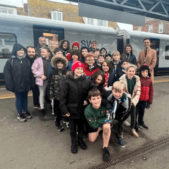 A group of school children and their teachers on a train platform