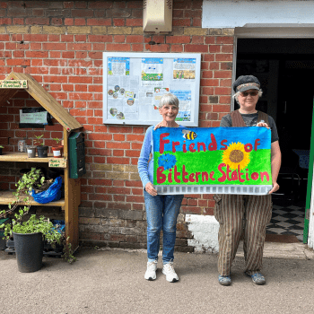 2 people holding a sign that says: 'friends of Bitterne Station' | South Western Railway