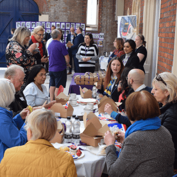 A group of people sat around a table eating | South Western Railway